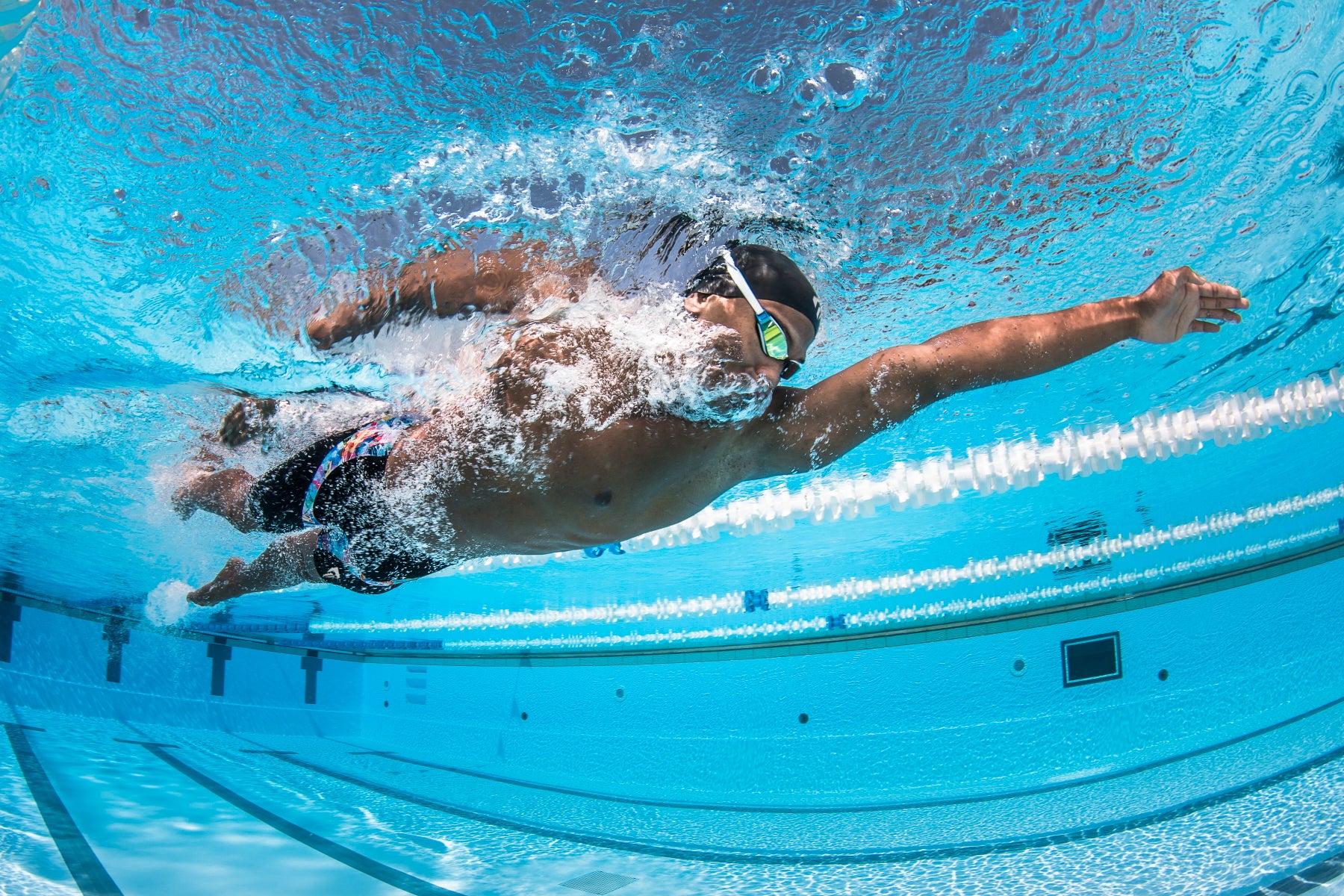 Ein Schwimmer aus der Unterwasserperspektive. Er streckt sich beim Kraulschwimmen lang nach vorn