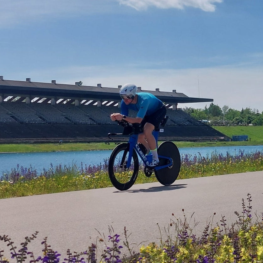 Ein Triathlet auf dem Rad in Zeitfahrposition entlang der Olympiaregattastrecke Oberschleißheim / München