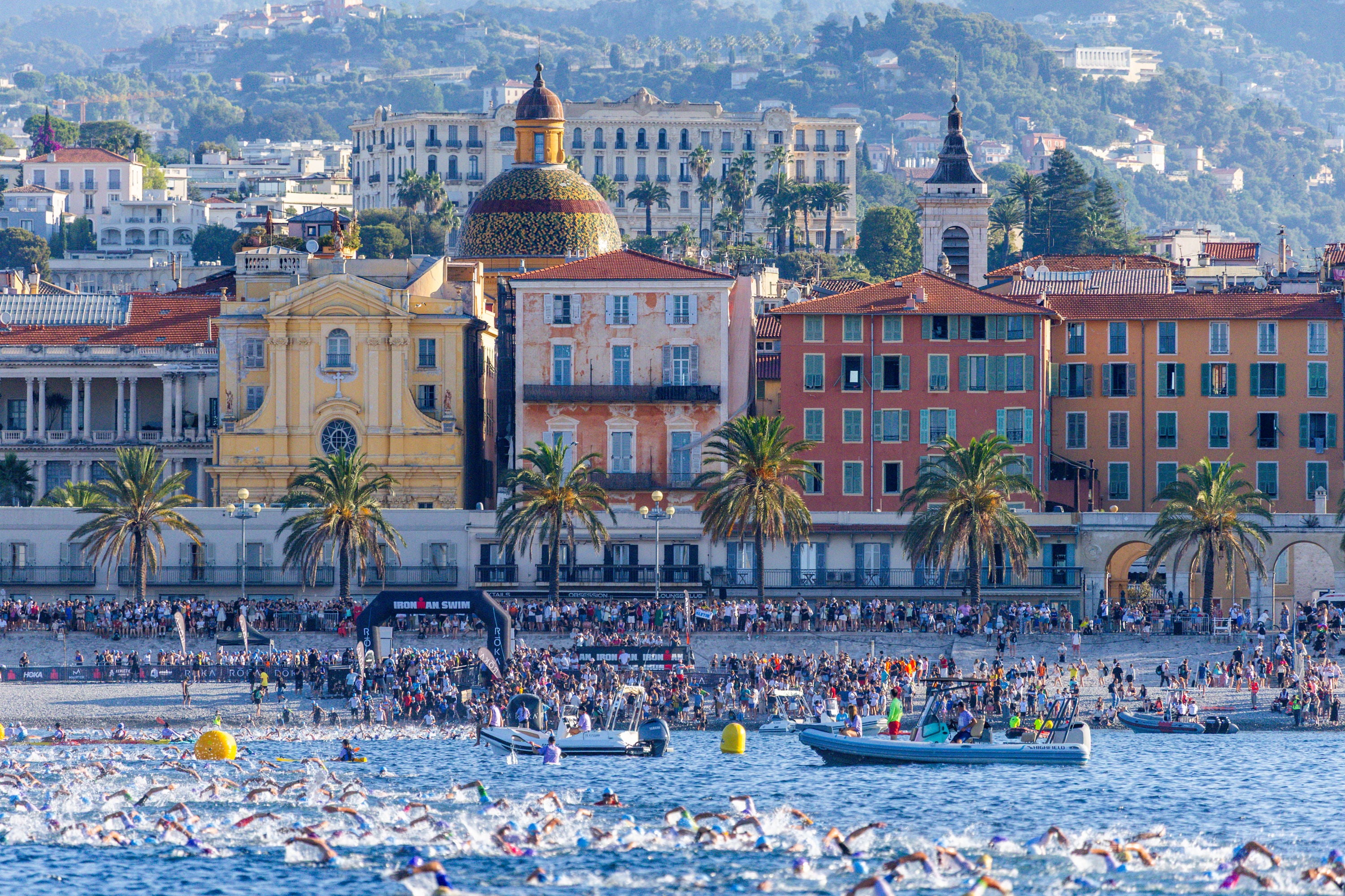 Schwimmer des 70.3 Ironman Nizza im Mittelmeer vor der beindruckenden Kulisse der Stadt fotografiert.