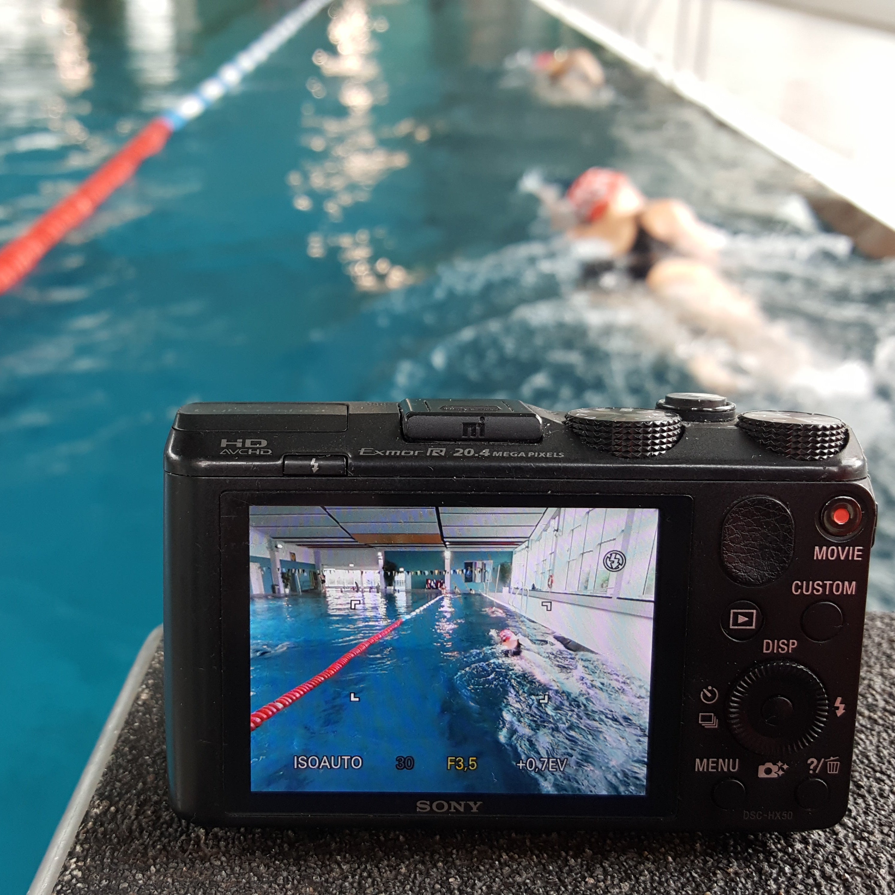 Eine Kamera steht auf einem Startblock und filmt die Schwimmerin beim Kraulschwimmen 