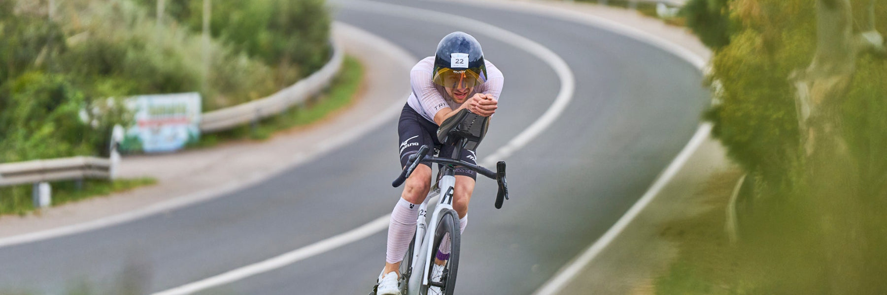 Triathlet Lukas Schnödewind auf seinem Triathlonrad in Aeroposition auf einer kurvigen Straße, Ansicht von schräg vorn