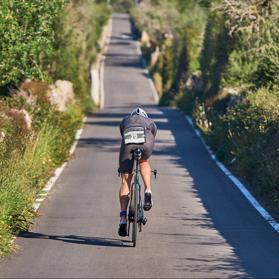 Ein Triathlet auf seinem Fahrrad von hinten fährt auf einer schmalen Straße durch das mallorcinische  Hinterland